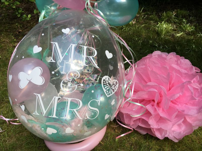 Transparenter Verpackungsballon mit Mr-and-Mrs-Motiv, kleinen Ballons und Schleifen in Pastellfarben